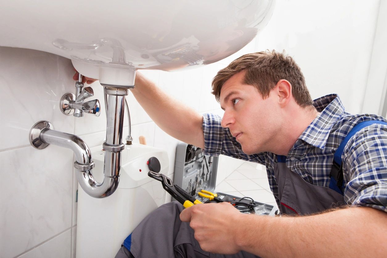 A man fixing the faucet of a sink.