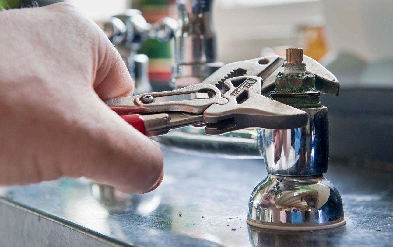 A person holding a pair of pliers over the top of a grinder.